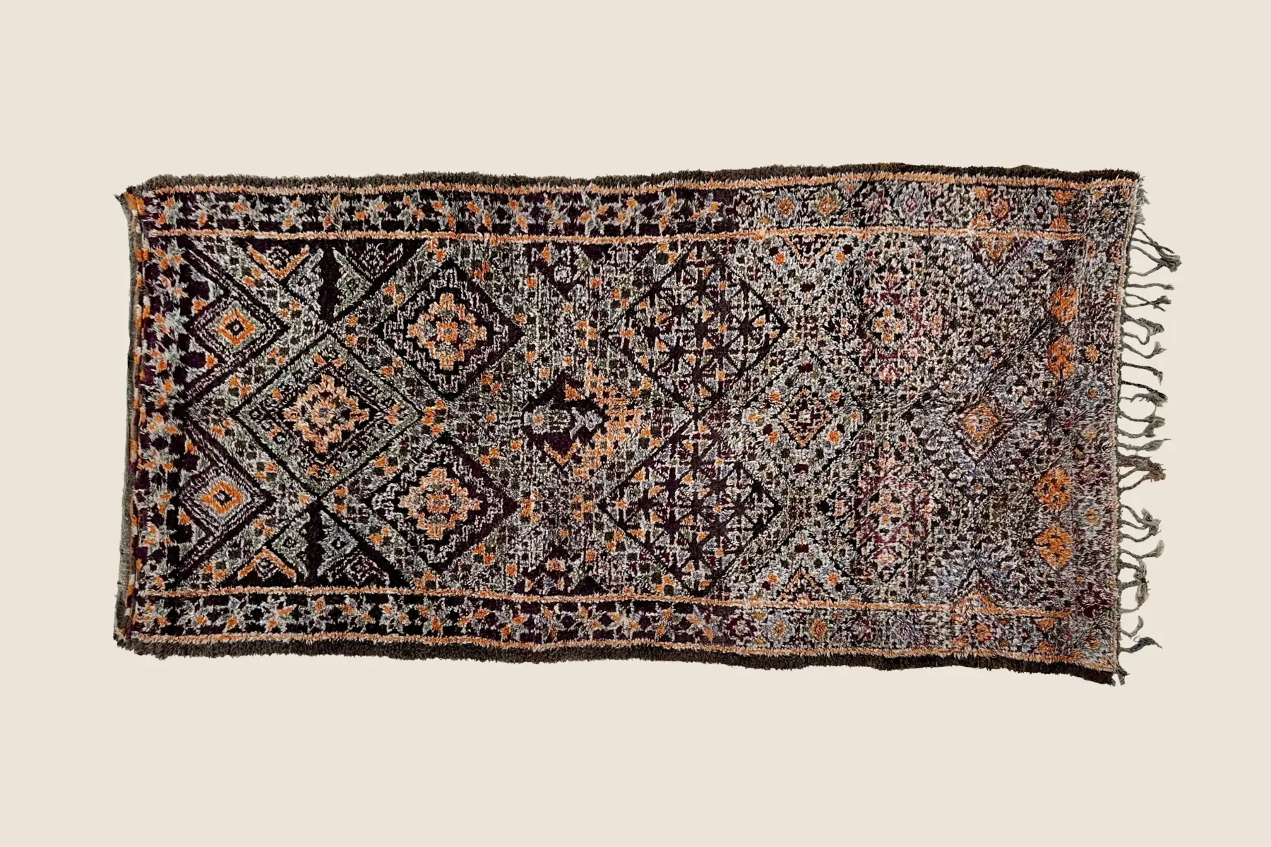 Beni M'Guild tribal rug detail showing hand-knotted wool texture with dark berry and warm orange geometric motifs
