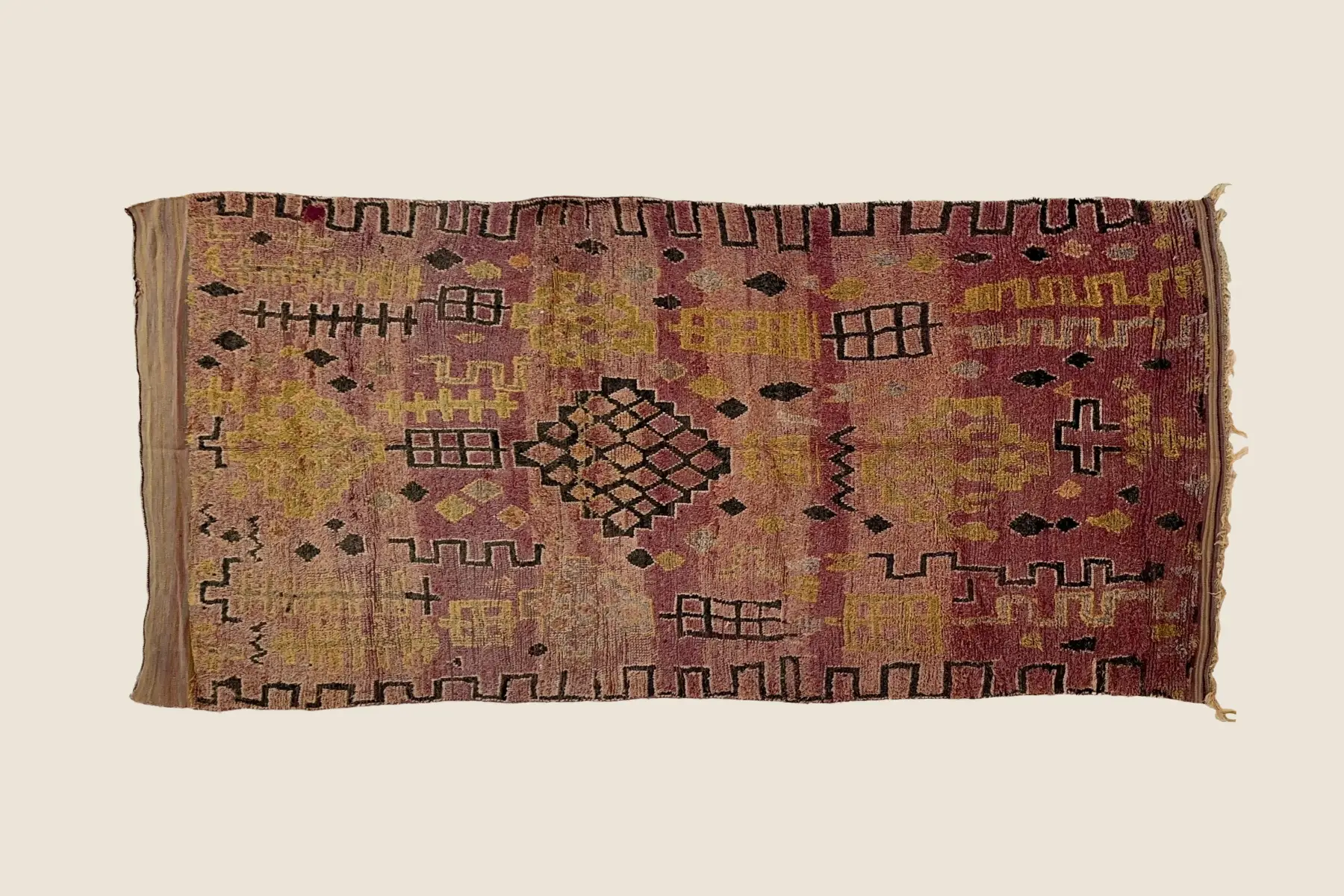 Talsint rug detail showing hand-knotted wool texture with dusty rose, warm gold, and dark gray color blending