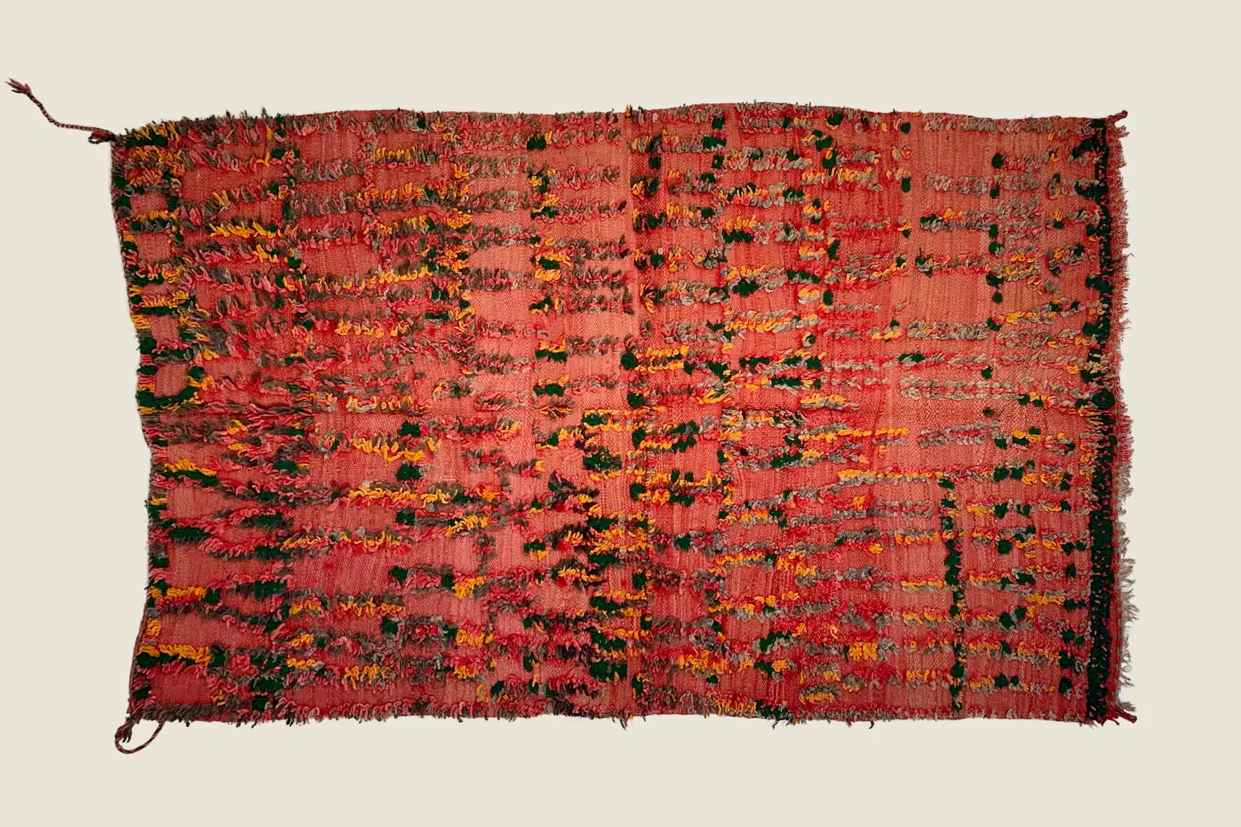 Talsint rug texture detail showing hand-knotted coral red wool and sage green pile